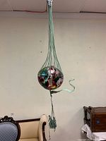 Full view of hanging hot air balloon sculpture showing blown glass multicolor balloon and patinated copper cage and basket.