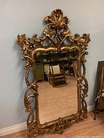 Full front view of mirror showing entire carved gilt wood frame and reflective surface
