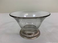 Side view of clear glass bowl with ribbed silver pedestal base.