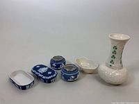 Full lot overview showing Wedgwood salt cellars and match boxes alongside Belleek bud vase and salt cellar/condiment dish.