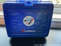 Front side of the blue plastic lunch box showing Toronto Blue Jays logo surrounded by player signatures and Loblaw branding below the logo.