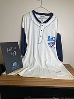 Full view of the men's Toronto Blue Jays baseball shirt displayed on a hanger with a lot number sign.
