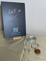 Full lot view showing eight silver-tone bangles, beaded bracelet, two pairs of earrings, and brown rose brooch on a beige surface