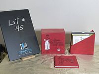 Photo showing red fabric-covered box, red CD slipcase with CDs partially visible, and matching hardcover book.