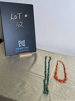 Both necklaces displayed side by side with a board indicating lot number