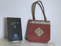 Front view of the burnt orange jute purse with leather handles and gold detailing.