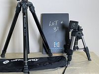 Vanguard Nivelo 244BK tripod fully extended next to OPTEX T25 tabletop tripod, with Vanguard carrying bag and lot information board behind