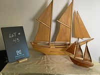 Photo showing two wooden ship models on a table against a white background, with a sign showing lot number 43.