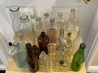 Photo showing the complete collection of glass bottles in various sizes and colors arranged against a white wall.