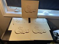 Four white vinyl LP record jackets with embossed Chicago logos arranged on a table with one standing upright.