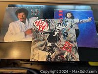 Three vinyl LPs on a black surface: Lionel Richie 'Dancing on the Ceiling', Hall & Oates with artistic cover and red text, and a third LP (Candi) with a person in a blue jacket on the cover.