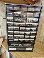 Front view of metal parts cabinet with 43 numbered drawers containing assorted small hardware items like screws, nuts, washers, and clips.