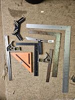 Full collection of assorted squares and measuring tools laid out on a carpet showing different sizes and types.