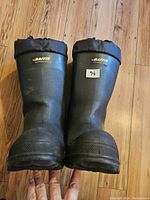 Front view of the black Baffin rubber boots showing their height and exterior condition.