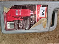 Grey molded plastic carrying case with worn label showing image and description of a red 6 ton hydraulic bottle jack.