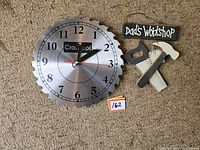 Front view of Craftsman circular saw blade styled wall clock and small 'Dad's Workshop' sign with wooden saw and hammer attached.