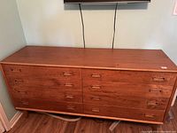 Front view of teak dresser showing eight drawers and integrated recessed handles