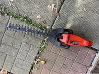 Photo of the hedge trimmer showing the full 20-inch bar and blade design lying on outdoor tiles.