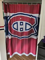 Photo of a red Montreal Canadiens shower curtain with a large official logo hanging on a rod.