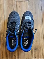 Top view of the New Balance shoes showing the black mesh upper, blue interior lining, and the size sticker on left shoe.