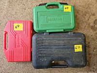 Three closed tool cases: green Hitachi, red unknown brand, black Mastercraft case.