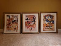 Group view of all three framed Disney art prints against wall