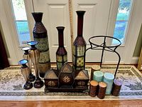 Front view of lot showing all items grouped including tall vases, candle holders, containers on stand, pillar candles, and metal plant stand