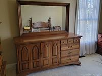 Dresser front view with mirror attached showing wood finish, cabinet doors and drawers