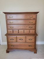 Front view of the wooden highboy dresser showing all drawers and brass handles.