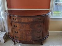 Front view of the curved wooden buffet showing four drawers with metal handles and scratches on the top surface.