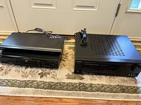 Two Sony DVD players and one Sony audio/video receiver on carpet, showing front views and power cords included. One DVD player includes remote.