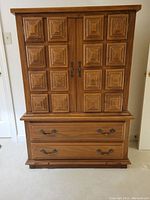 Front view of the mid-century oak highboy dresser with layered square panel details on doors and two bottom drawers with metal handles.