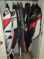 Group of leather motorcycle jackets on hangers including Dainese, Alpinestars, Ducati by Dainese and Rev'It!.