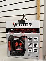Front view of the boxed Vector 3-in-1 Portable Power Jump Starter showing main features and specifications including 700A peak battery, 12V DC power, 2.1 AMP USB power, and compatibility with up to 4.6L cylinder engines.