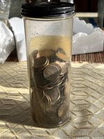 Clear plastic container filled with numerous wheat pennies.