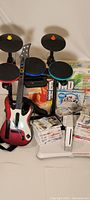Drum kit, guitar controller, Wii console, Balance Board, GameTablet, controllers and stack of game cases.