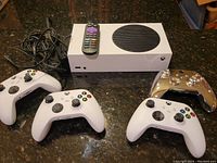 Console, four controllers, remote and cables on countertop