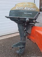 Left side view of Scott-Atwater 16HP Bail-a-matic outboard motor showing yellow top cover and green body with mounting bracket visible.