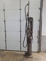 Full front view of the vertical gas pump showing base, cylinder and hose