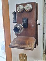 Front view showing two metal bells, black mouthpiece, wood shelf, handset, and oak case.