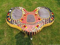 Top-down views of Airhead Transformer 3 tow behind inflatable tube placed on grass, showing detailed color pattern and attachment point.