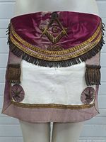 Front view of the antique Masonic apron highlighting velvet top flap with embroidered square and compass symbol, Lodge 426 number, and decorative gold trim and fringe.