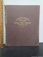 Front cover of the atlas showing brown cloth with gold embossed text and signs of wear.