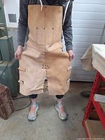 Person holding the heavy leather apron in front showing full length and pocket arrangement