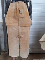 Front view of the heavy leather apron showing the pocket with Power Fist logo and the overall tan leather material.