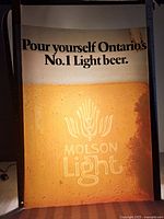 Full view of lighted advertising insert showing text and beer image.