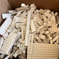 Close-up photo showing various white LEGO bricks including plates, bricks, and some specialty pieces inside box 1.