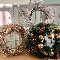 Photo showing all three wreaths together: natural twig wreath, green pine wreath with gold decorations, and frosted icicle faux grapevine wreath