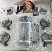 Photo of the full set including French press, cups, spoons, coasters and pouring cup all in original packaging