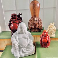 Lot of five Asian figurines displayed together: four Buddha figurines and one wooden Fukurokuju figurine from Japan.